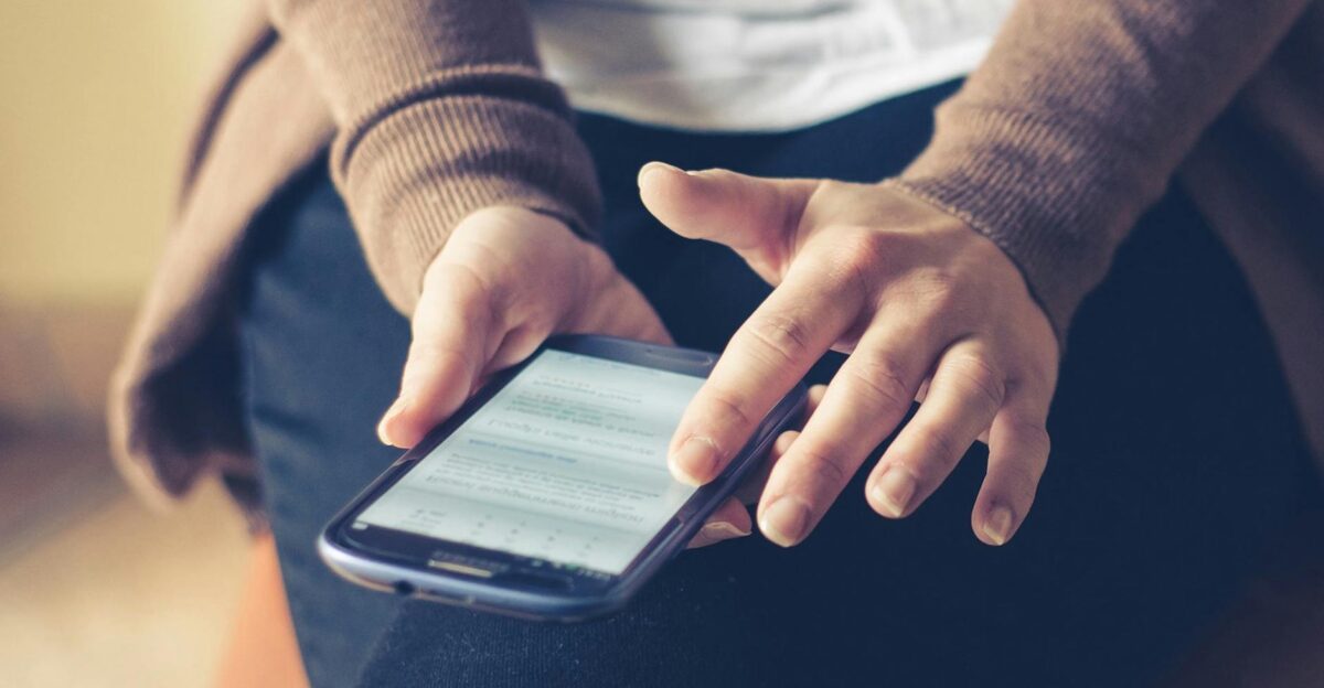 Close-up of adult using smartphone indoors browsing web with focus on screen