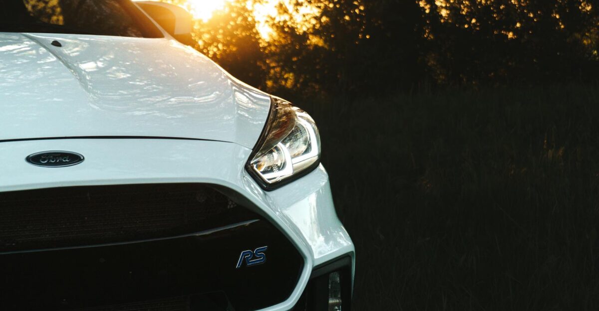 Close-up of a white Ford car amidst a serene outdoor setting at sunset