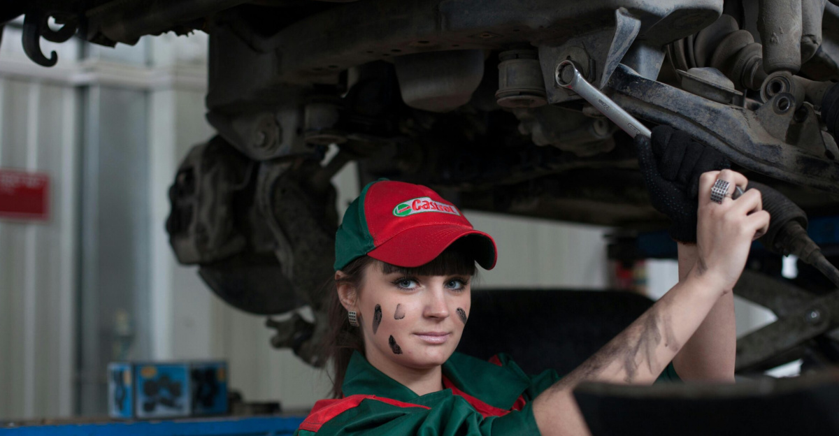 Female mechanic maintaining a car in an auto repair shop, showcasing skill and concentration.