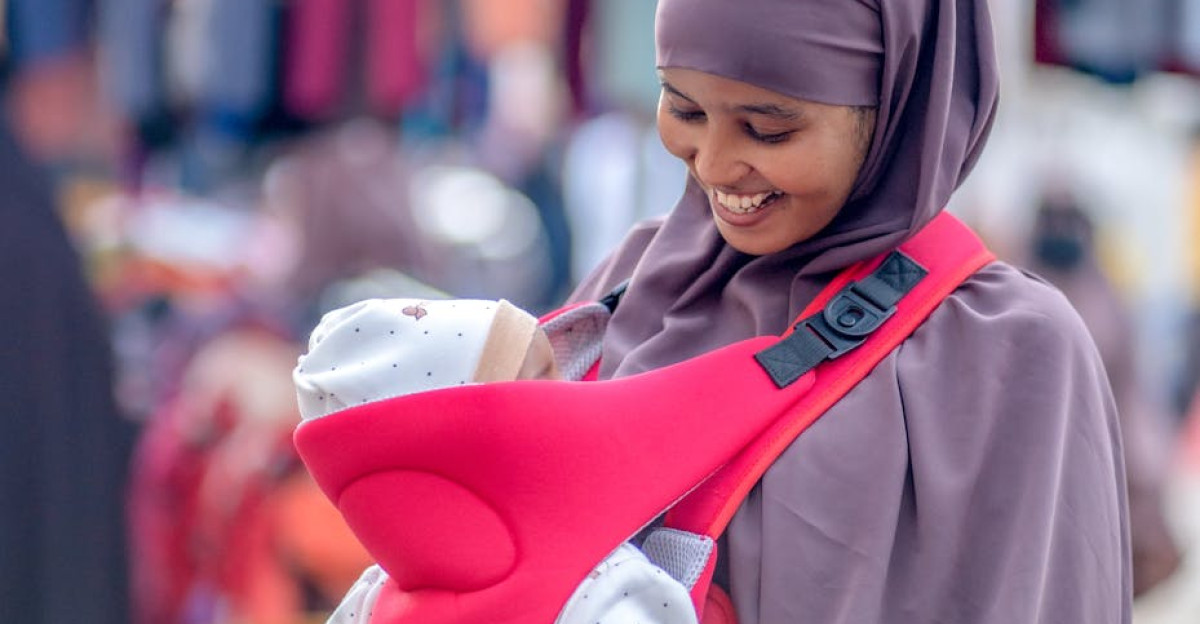 A joyful Somali mother wearing a hijab cradles her baby outdoors in a bustling market in Mogadishu Somalia