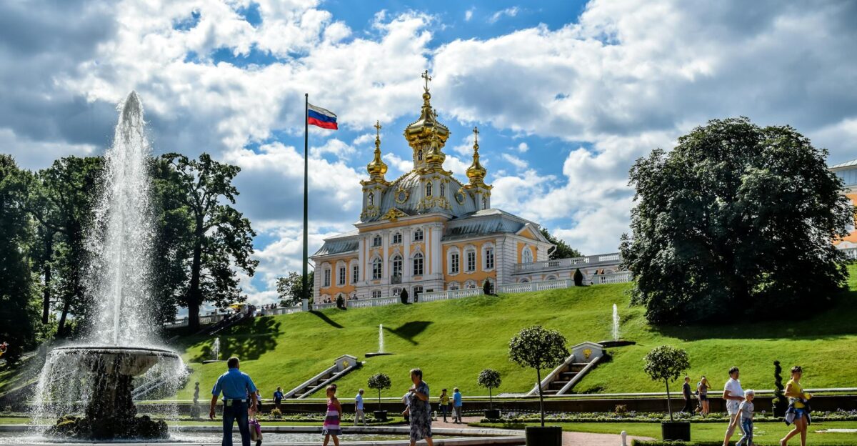 A vibrant summer scene at Peterhof Palace gardens with fountains and visitors enjoying the sunny day