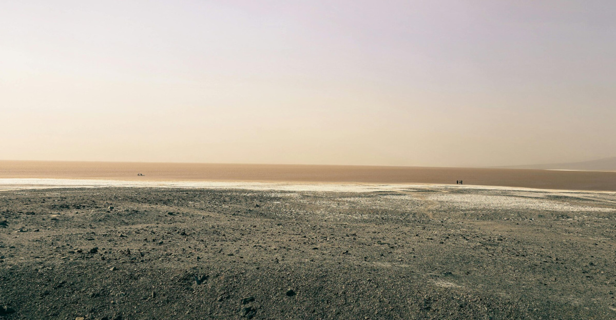 Expansive view of Death Valley's dry desert terrain with a hint of a seasonal lake in the distance.