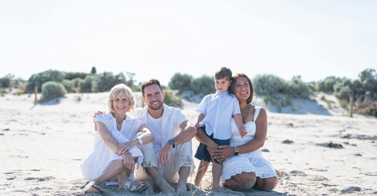 A joyful family sitting together on a sandy beach under the bright sun