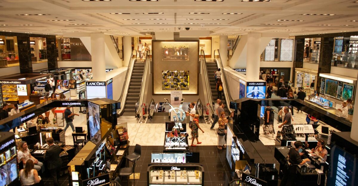 A bustling scene inside a modern shopping mall with escalators and various retail stalls