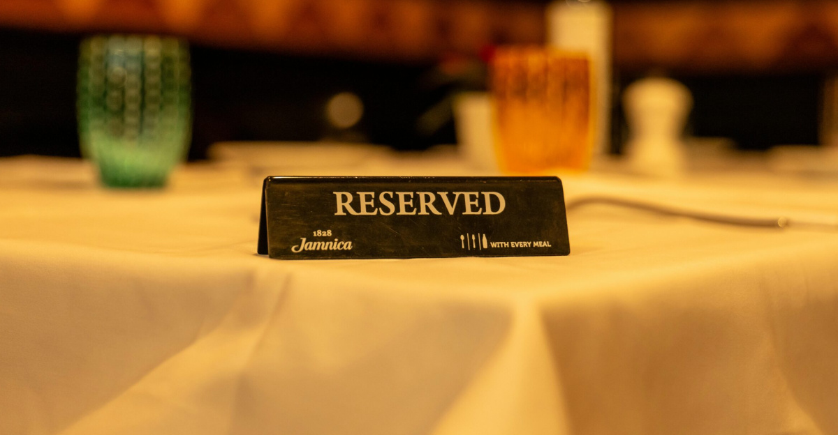 Close-up of a reserved sign on a white tablecloth in a dimly lit restaurant setting.