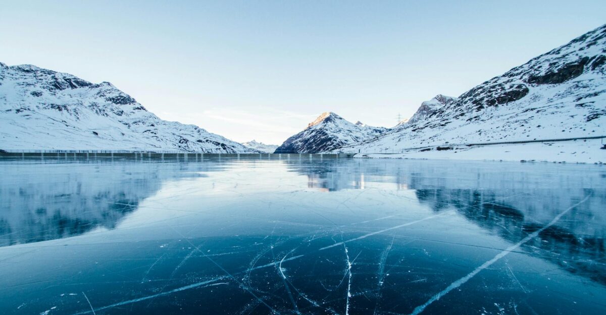 A serene winter landscape featuring a frozen lake surrounded by snow-covered mountains in Switzerland