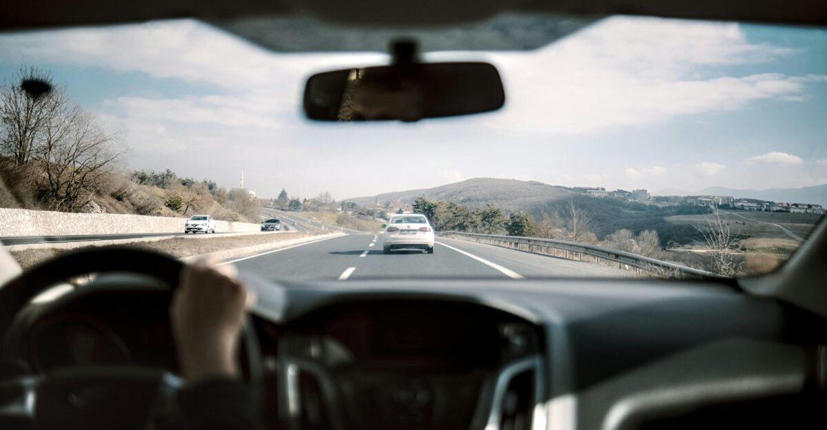 View from a car driving down a scenic highway with hills in the background depicting a casual road trip