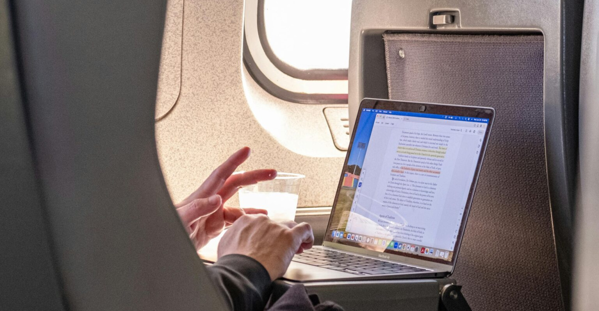 Passenger working on a laptop during flight, highlighting travel productivity.