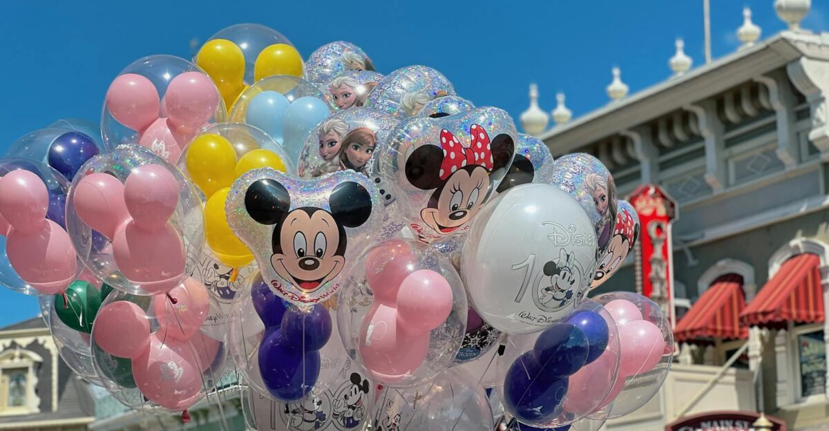 Vibrant Disney character balloons in front of theme park cinema under blue sky