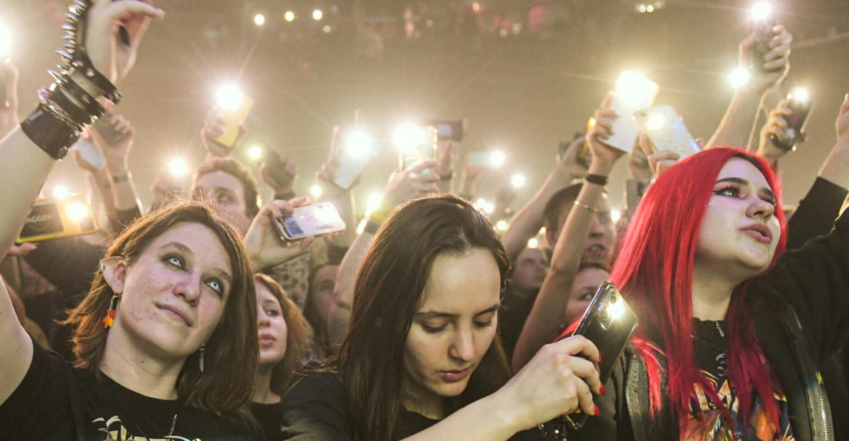 Fans enjoying a live rock concert, capturing moments with cell phones.