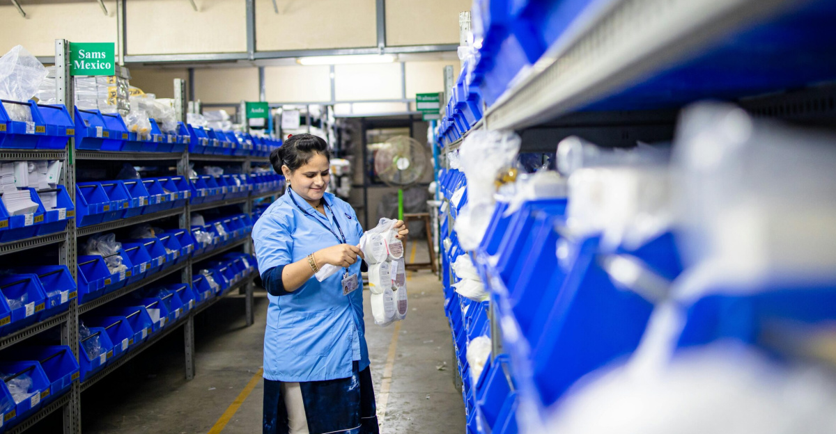 Female worker organizes shelves in a warehouse. Industrial setting with labeled storage bins.