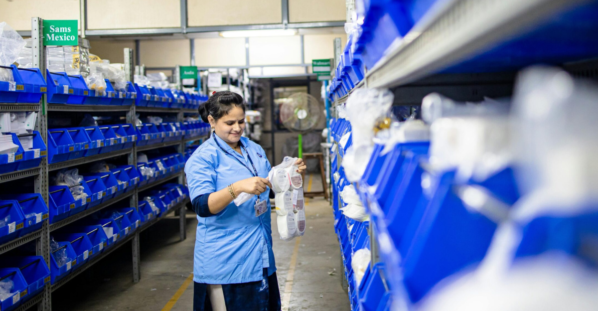 Female worker organizes shelves in a warehouse. Industrial setting with labeled storage bins.