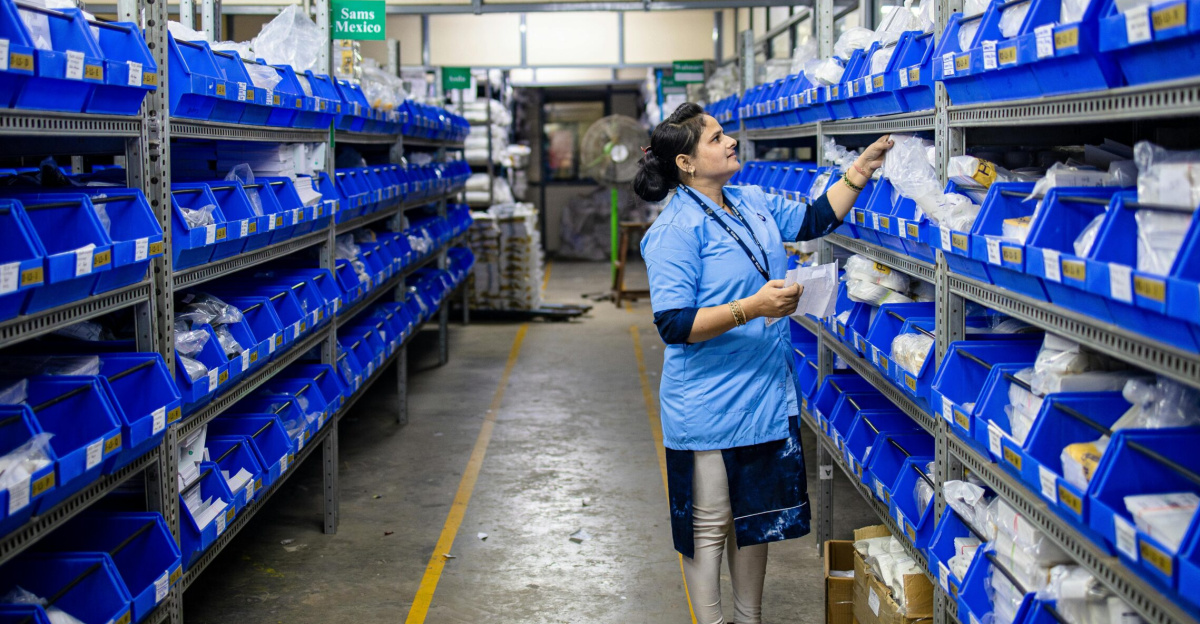 A worker in a warehouse organizing inventory on shelves with blue bins.