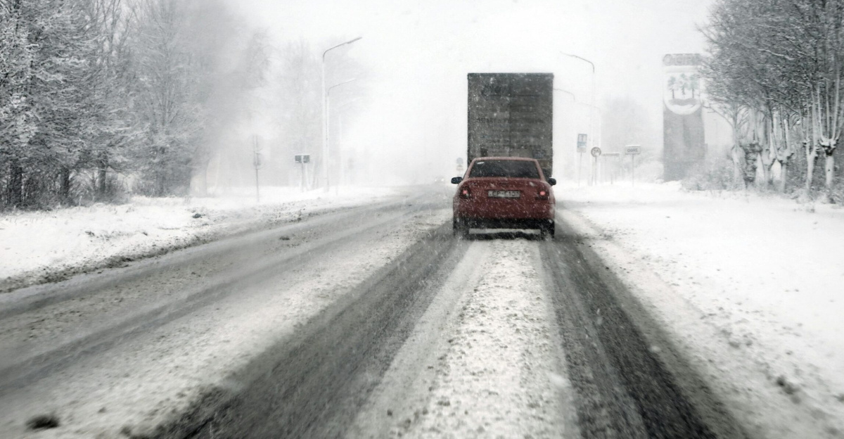 Cars navigate a snowy highway during a blizzard, showcasing tough winter driving conditions.