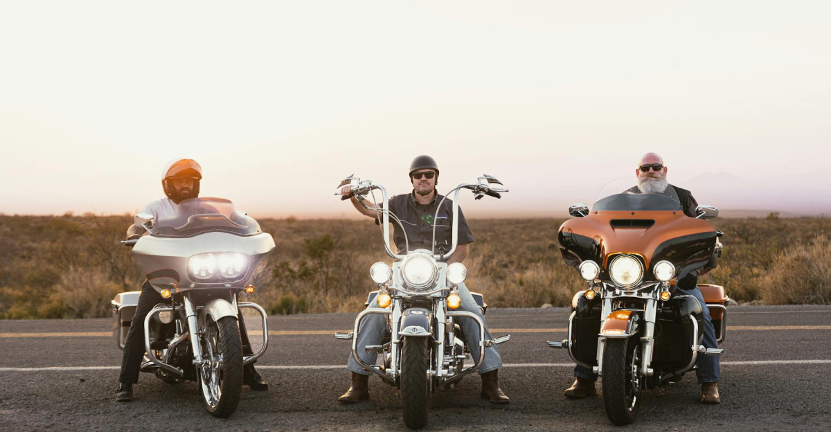 Three bikers on motorcycles riding on a scenic road during sunset in New Mexico
