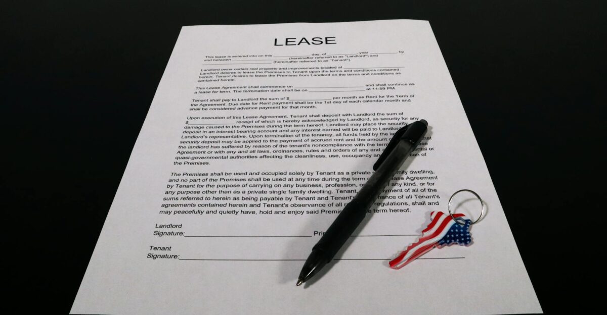 Lease agreement document with pen and American flag keychain on a black table