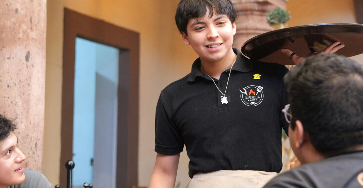 A cheerful waiter interacting with customers at a restaurant in Guanajuato, Mexico.