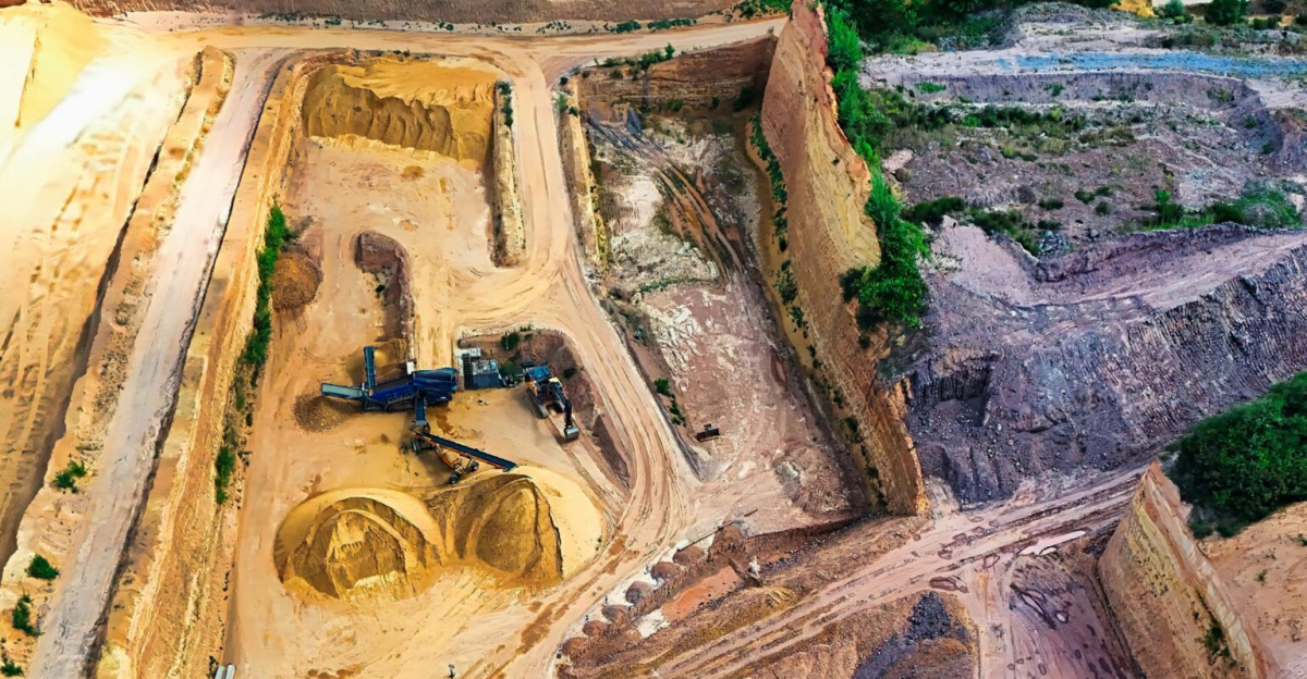Aerial view of a large sandstone quarry with heavy machinery digging and piles of sand.