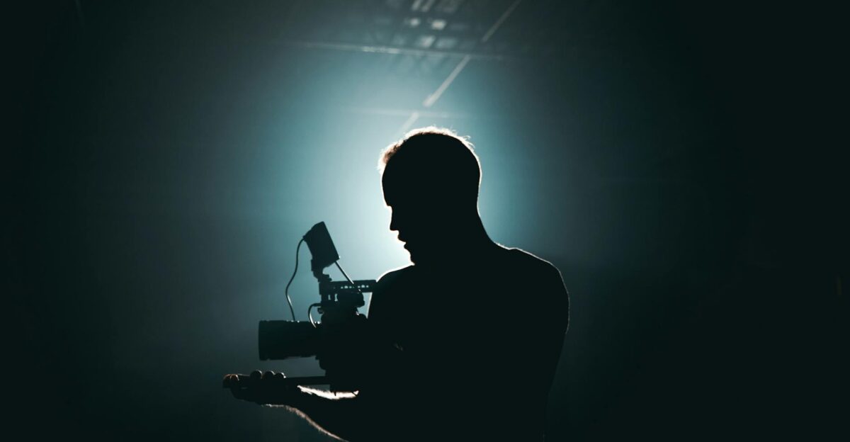 Silhouette of a cinematographer with camera gear in a dramatic low light setting