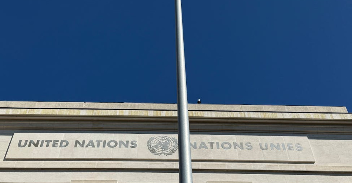 Blue UN flag waving outside United Nations headquarters in Geneva Switzerland under a clear blue sky