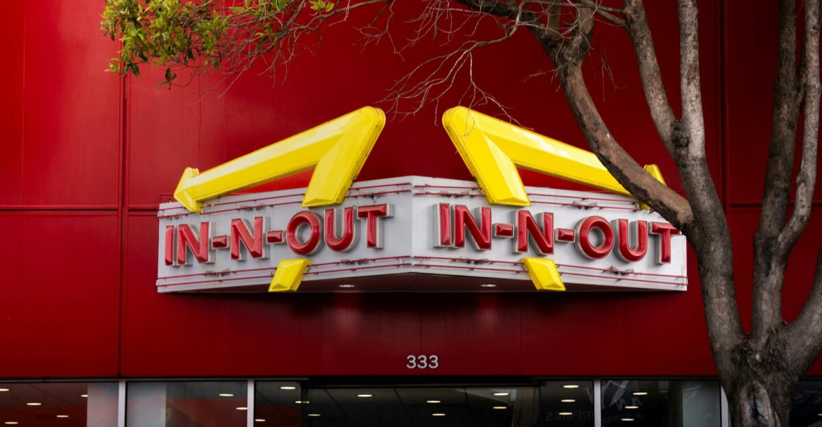 Iconic In-N-Out Burger sign with bold red background and trees in the foreground