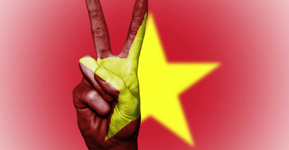 Hand showing peace sign with Vietnamese flag overlay symbolizing unity and patriotism