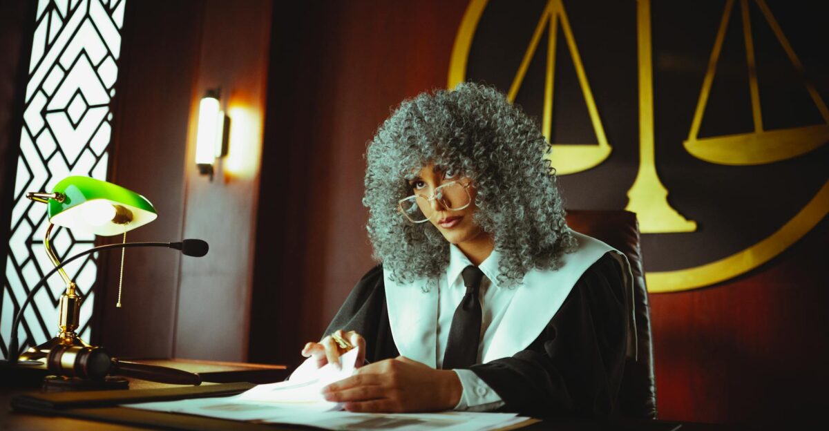 A judge in a courtroom examining documents under a classic green lamp