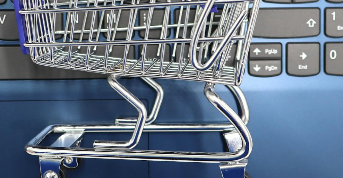 A miniature shopping cart placed on a laptop keyboard symbolizing online shopping and e-commerce