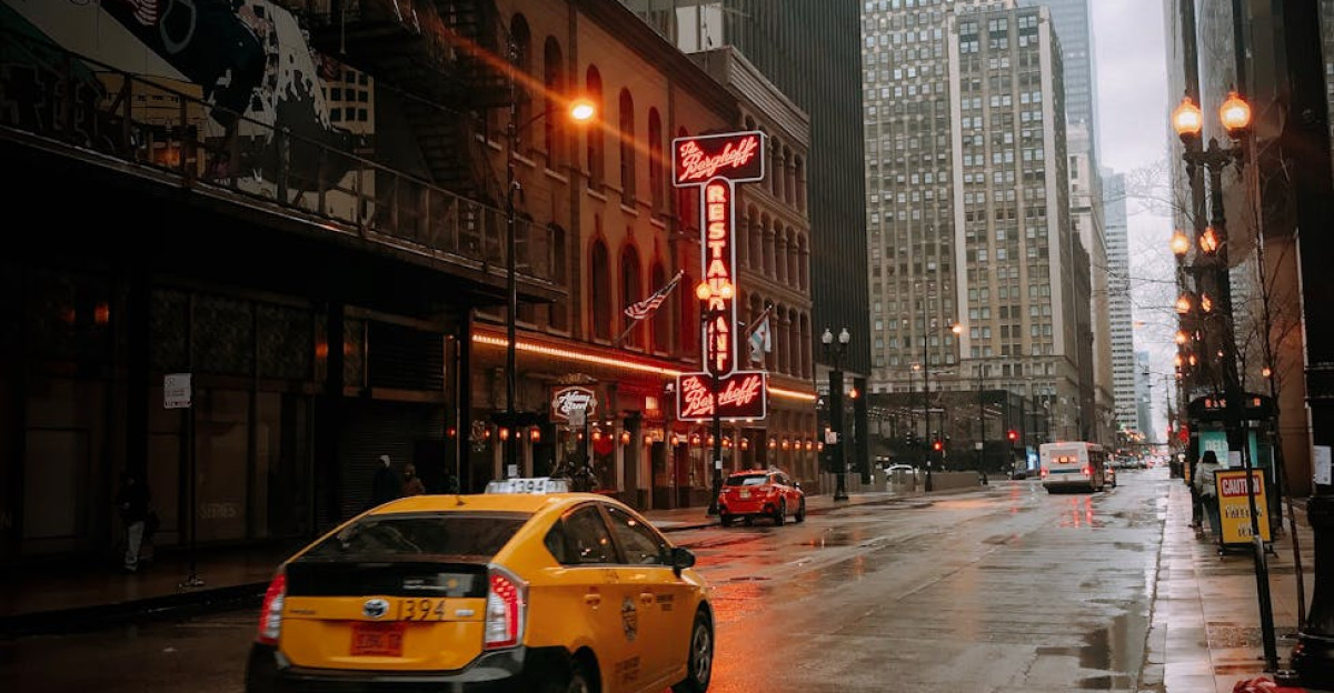 A yellow taxi navigates a rainy street in downtown Chicago surrounded by towering skyscrapers