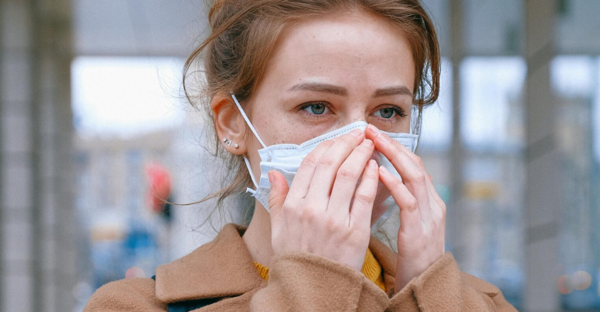 Woman in coat wearing a mask outdoors, symbolizing pandemic safety measures.
