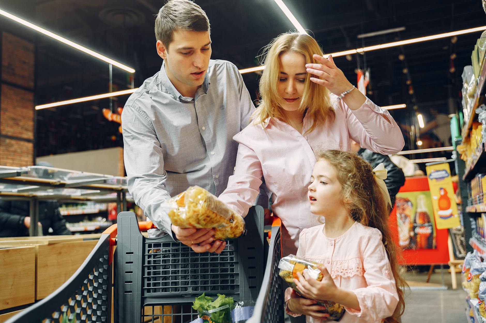 A family enjoying shopping in a supermarket aisle selecting groceries with a cart