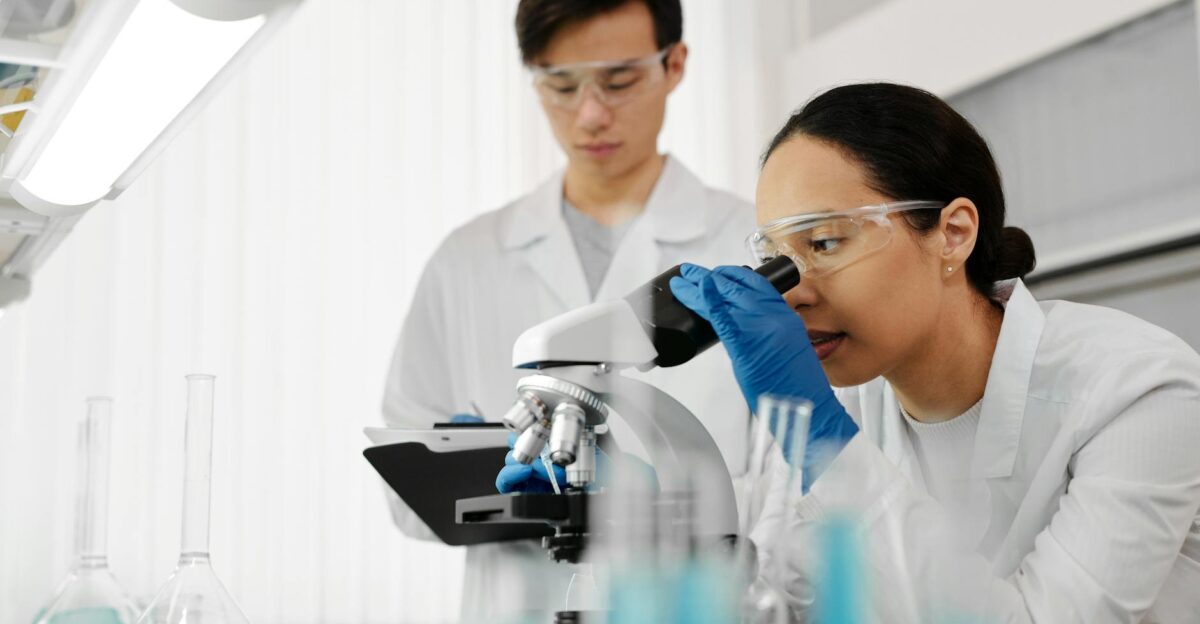 Two scientists in a laboratory using a microscope and analyzing samples