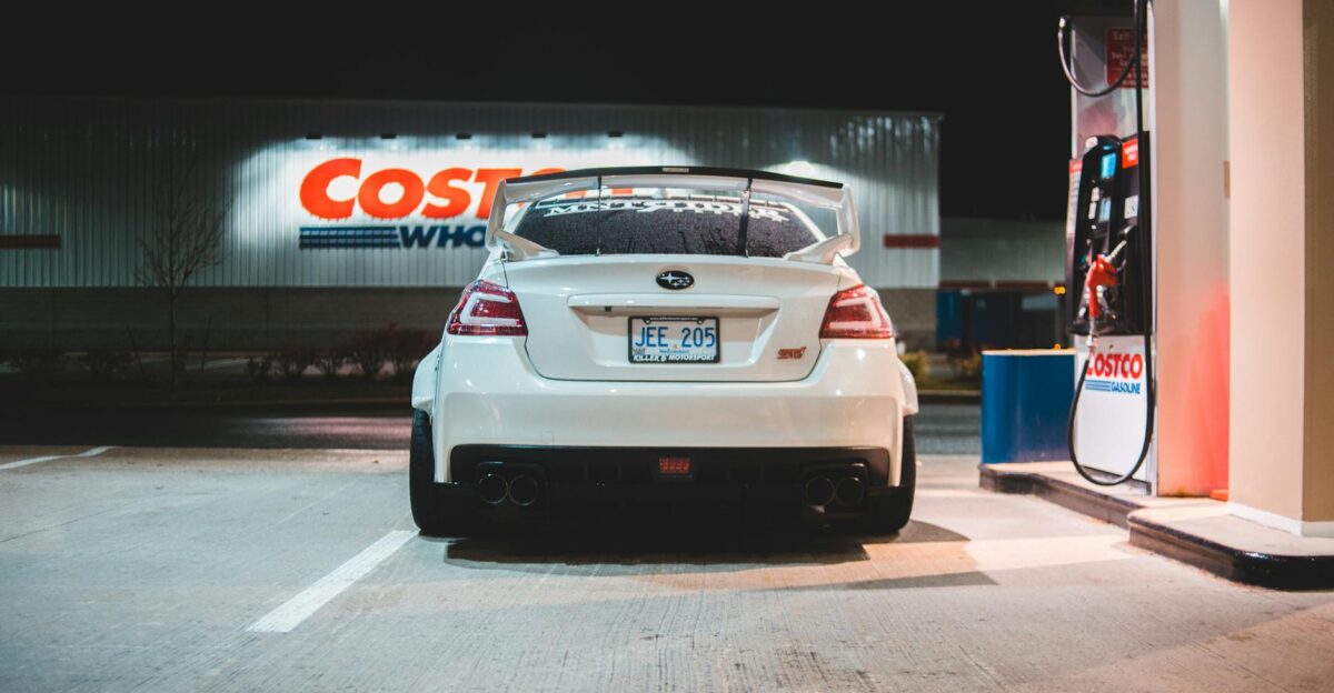 Contemporary white car parked near pump on fuel station at night in city