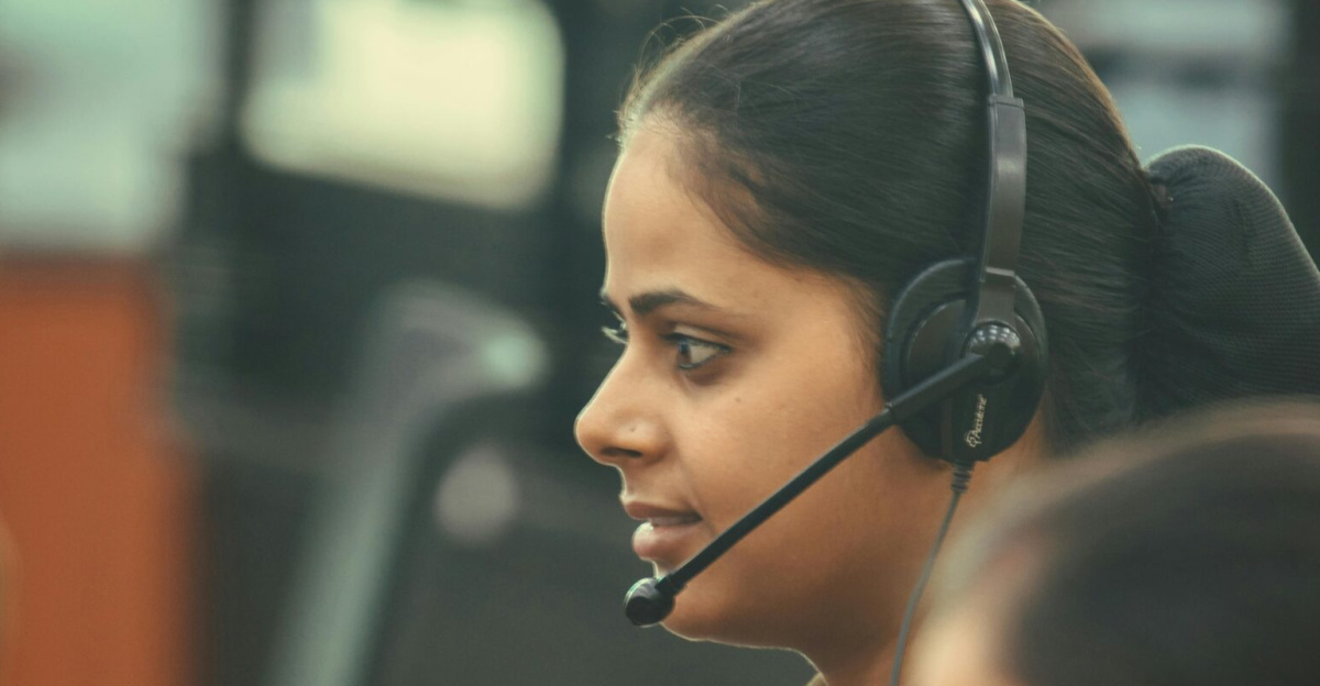 Side view of a call center agent wearing a headset, working diligently in a busy office environment.