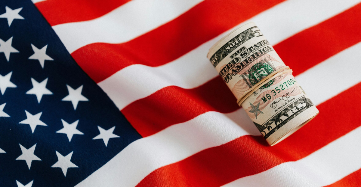 From above of United States currency folded in roll placed on USA flag illustrating concept of business profit and wealth