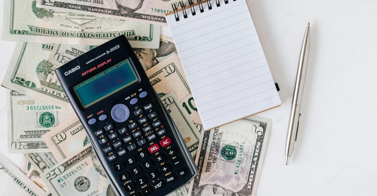 Flat lay of US dollar bills with calculator and notebook for budgeting.