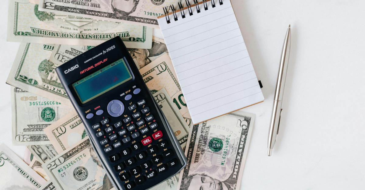 Flat lay of US dollar bills with calculator and notebook for budgeting.