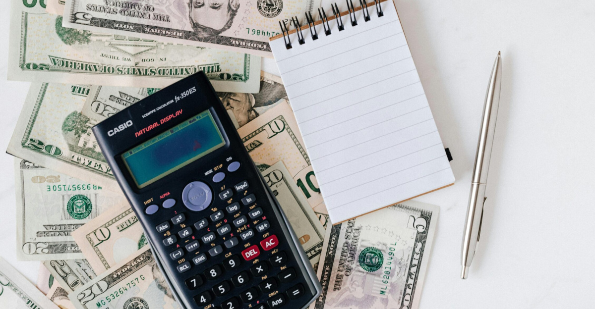 Flat lay of US dollar bills with calculator and notebook for budgeting.