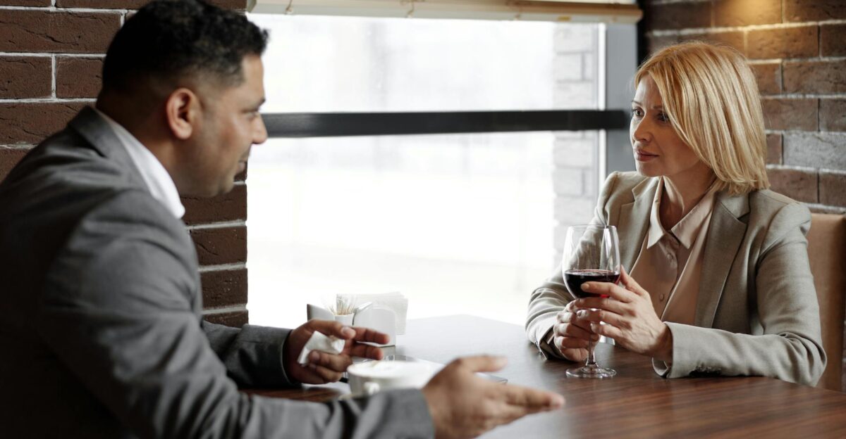 Two business professionals discussing ideas over a glass of wine in a modern caf setting