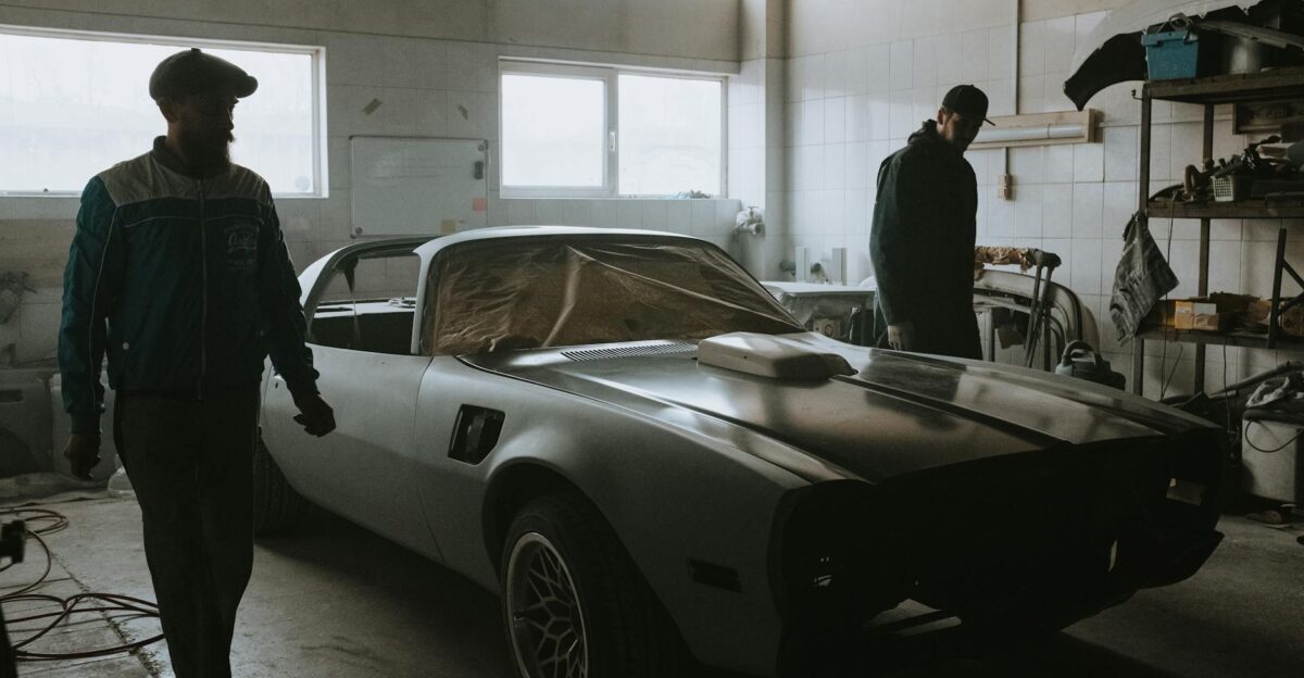 Mechanics working on a vintage car restoration in a dimly lit garage capturing the essence of classic automotive care