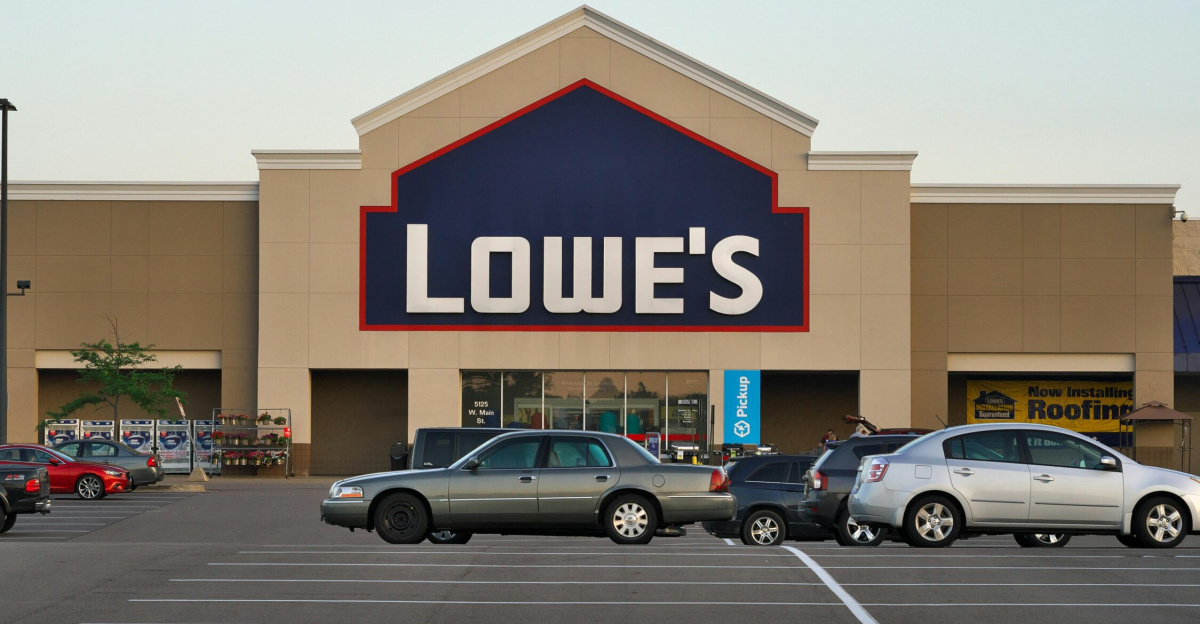 Front view of a Lowe's store entrance with parked cars in the lot during the day.