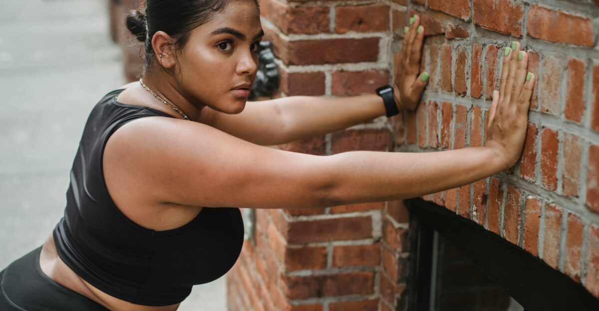 Fit woman in athletic wear performing a wall push-up on a city street