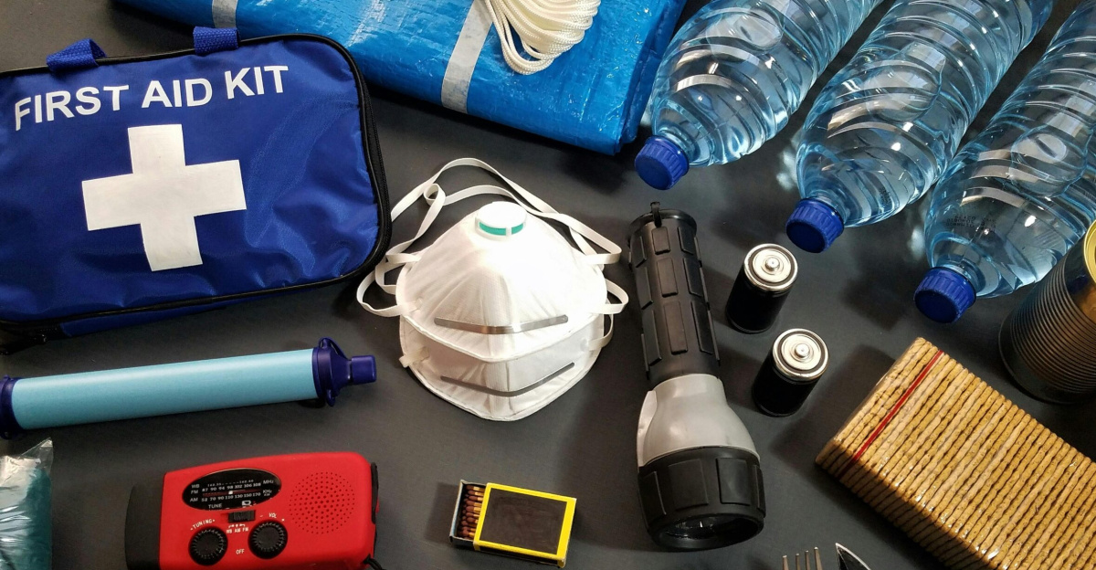 Flat lay of essential emergency survival kit items including first aid and water bottles.