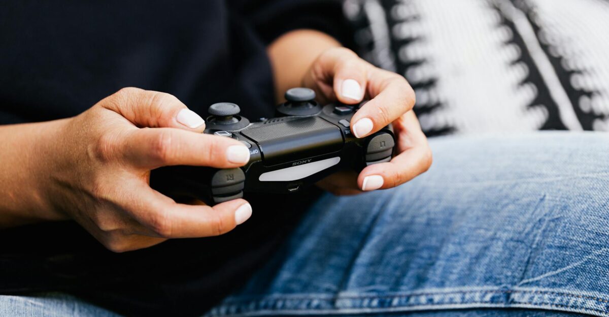 A person playing video games with a close-up of their hands holding a gaming controller