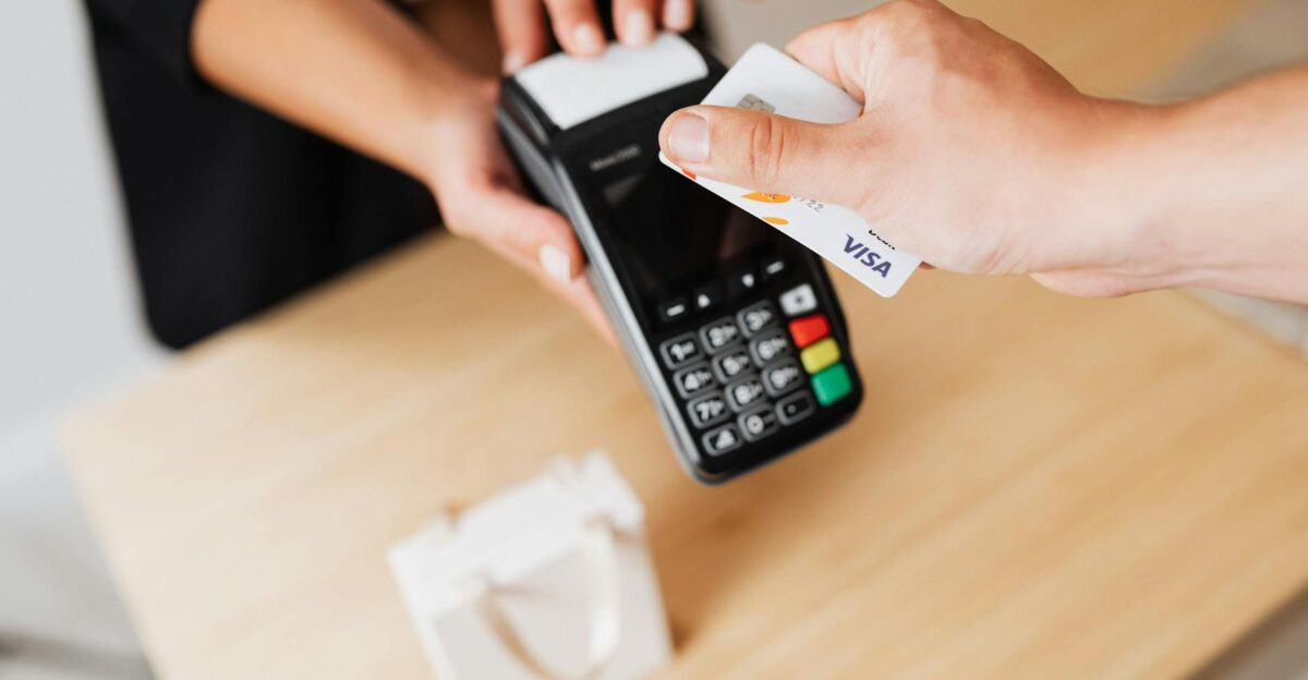 Close-up of hands using a contactless payment terminal with a credit card indoors
