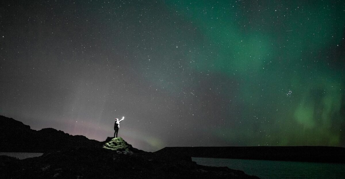 A person stands under the stunning aurora borealis in Iceland s night sky