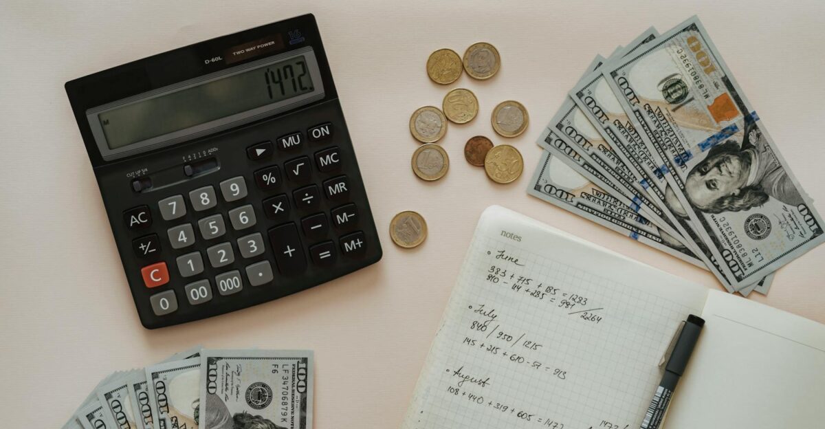 Flat lay of calculator cash coins and handwritten notes for budget planning