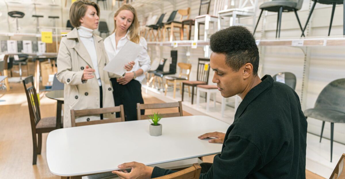 A professional discussion takes place in a well-lit furniture store showroom with diverse employees