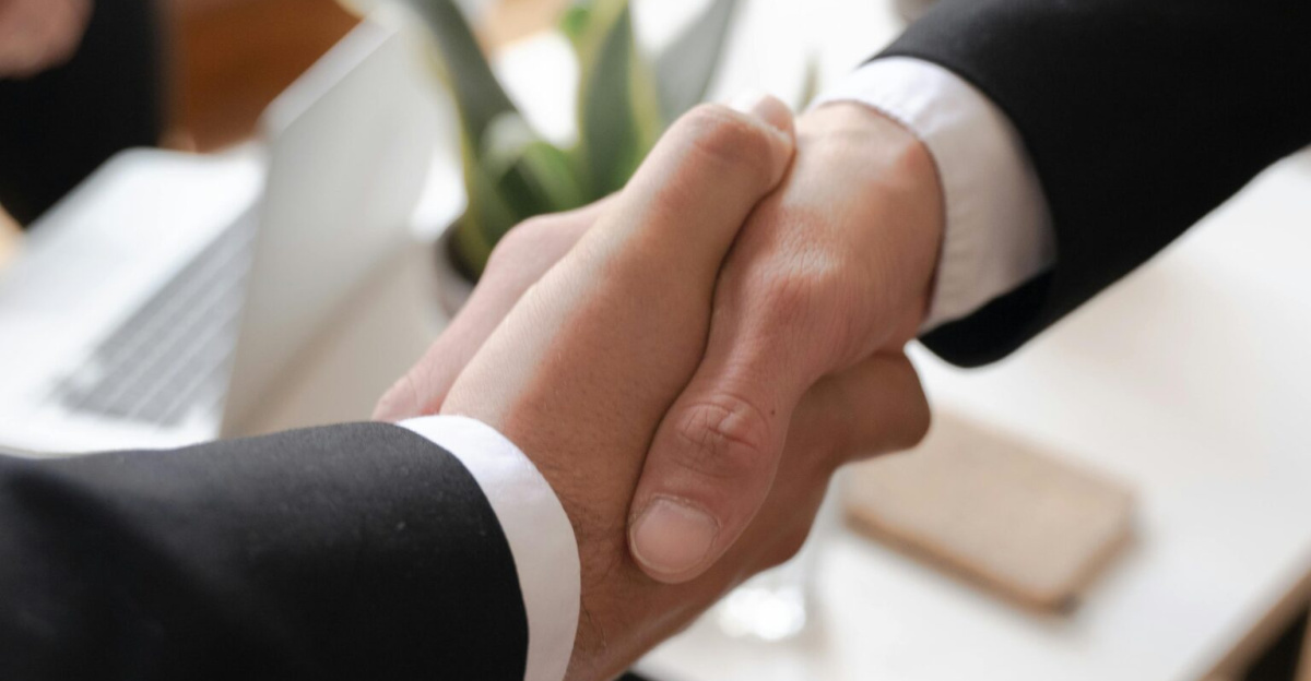 Close-up of a handshake between two professionals in a business setting, symbolizing agreement.