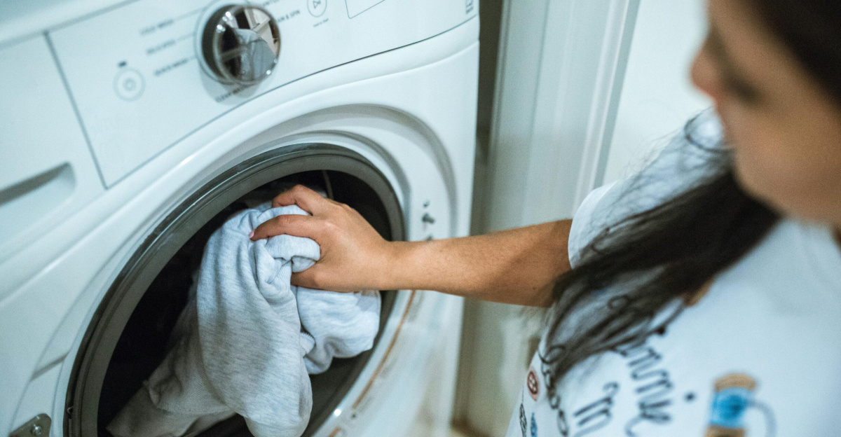 A woman loading laundry into a washing machine indoors, focusing on household chores.